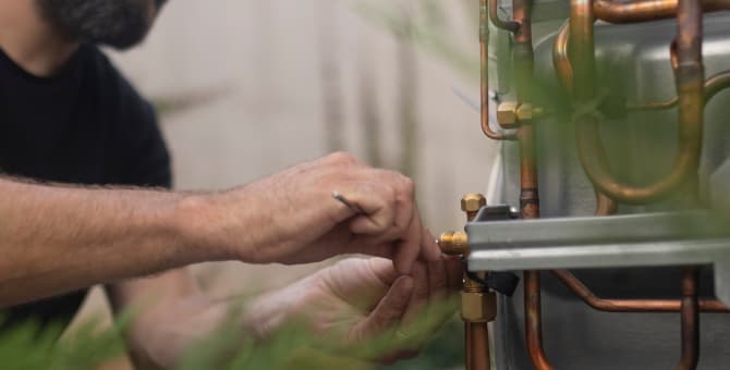 Service repair person adjusting an air conditioning unit with a tool